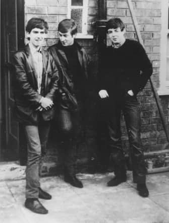 circa 1960:  Liverpudlian skiffle beat band The Beatles standing outside Paul's Liverpool home (left to right) George Harrison (1943 - 2001), John Lennon (1940 - 1980), Paul McCartney. Ringo Starr was not to join the band for another two years.  (Photo by Keystone/Getty Images)