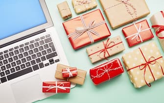 High angle view of a laptop computer and gifts on turquoise background, online shopping