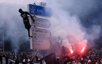 epa10717471 A person climbs a traffic sign as others hold flares during a march in the memory of 17-year-old Nahel, who was killed by French Police in Nanterre, near Paris, France, 29 June 2023. Violence broke out after the police fatally shot a 17-year-old during a traffic stop in Nanterre on 27 June. According to the French interior minister, 31 people were arrested with 2,000 officers being deployed to prevent further violence.  EPA/YOAN VALAT