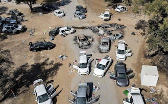 This aerial picture shows abandoned and torched vehicles at the site of the October 7 attack on the Supernova desert music Festival by Palestinian militants near Kibbutz Reim in the Negev desert in southern Israel on October 13, 2023. One month after Israel was wracked by Hamas attacks, life has been upended for both the Palestinians and Israel after it launched a war of reprisal in the Gaza Strip. The October 7 attacks by Hamas militants who stormed across from Gaza and struck kibbutzim and southern Israeli areas killed 1,400 people, mostly civilians, and deeply scarred the nation. The health ministry in Hamas-run Gaza says nearly 9,500 have been killed, two-thirds of them women and children, and mostly civilians. (Photo by Jack GUEZ / AFP)