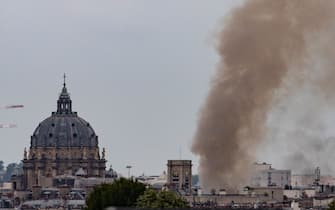 TOPSHOT - This general view shows smoke rising from a building at Place Alphonse-Laveran near the Dome of the Val de Grace (L) in the 5th arrondissement of Paris, on June 21, 2023. A major fire of unknown origin broke out on June 21, 2023 in a building in central Paris, part of which collapsed, injuring at least one person, according to sources and AFP images. (Photo by Ian LANGSDON / AFP) (Photo by IAN LANGSDON/AFP via Getty Images)