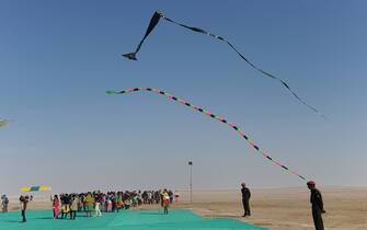 Kites fly over visitors during the International Kite Festival near Dhordo village, close to the India-Pakistan border, some 500 kms from Ahmedabad, on January 10, 2014. The International Kite Festival is taking place across the state of Gujrat. AFP PHOTO/Sam PANTHAKY        (Photo credit should read SAM PANTHAKY/AFP via Getty Images)