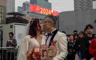 A newlywed couple is kissing in front of an electronic display board that shows 2024 in Hong Kong, China, on December 31, 2023. (Photo by Vernon Yuen/NurPhoto)