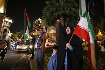 Demonstrators wave Iran's flag and Palestinian flags as they gather at Palestine Square in Tehran on April 14, 2024, after Iran launched a drone and missile attack on Israel. Iran's Revolutionary Guards confirmed early April 14, 2024 that a drone and missile attack was under way against Israel in retaliation for a deadly April 1 drone strike on its Damascus consulate. (Photo by ATTA KENARE / AFP) (Photo by ATTA KENARE/AFP via Getty Images)