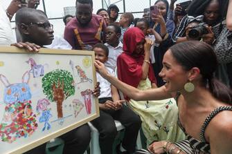 Britain's Meghan (R), Duchess of Sussex, receives an artwork upon her arrival with Britain's Prince Harry (unseen), Duke of Sussex, for an exhibition sitting volleyball match at Nigeria Unconquered, a local charity organisation that supports wounded, injured, or sick servicemembers, in Abuja on May 11, 2024 as they visit Nigeria as part of celebrations of Invictus Games anniversary. (Photo by Kola SULAIMON / AFP) (Photo by KOLA SULAIMON/AFP via Getty Images)