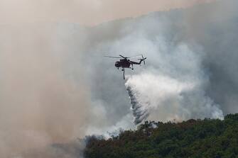 A firefighting helicopter drops water over a wildfire near the village of Leptokaria, Alexandroupolis, Greece, on Monday, Aug. 28, 2023. With more than 72,000 hectares burnt, the Alexandroupolis wildfire in Evros is the largest on record in the EU. Photographer: Konstantinos Tsakalidis/Bloomberg via Getty Images