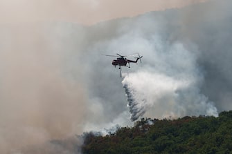 A firefighting helicopter drops water over a wildfire near the village of Leptokaria, Alexandroupolis, Greece, on Monday, Aug. 28, 2023. With more than 72,000 hectares burnt, the Alexandroupolis wildfire in Evros is the largest on record in the EU. Photographer: Konstantinos Tsakalidis/Bloomberg via Getty Images