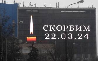 An advertising screen on the facade of a building displays an image of a lit candle and the slogan "(We) Mourn" in memory of victims of the concert hall gun attack in Moscow on March 23, 2024. Gunmen who opened fire at a Moscow concert hall killed more than 60 people and wounded over 100 while sparking an inferno, authorities said on March 23, 2024, with the Islamic State group claiming responsibility. (Photo by Olga MALTSEVA / AFP) (Photo by OLGA MALTSEVA/AFP via Getty Images)