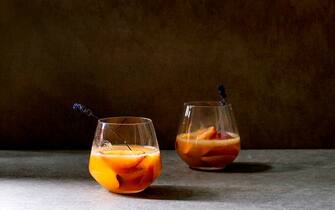 Peach cold lemonade or Bellini cocktail with lavender flowers served in two glasses on dark texture table. Homemade summer drink. Copy space. (Photo by: Natasha Breen/REDA&CO/Universal Images Group via Getty Images)