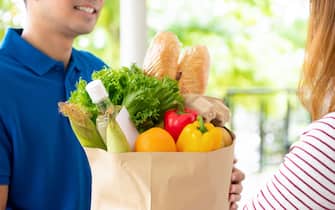 Groceries delivered to customer at home by a delivery man, for online food service concept