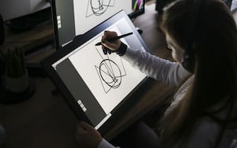 Young woman working at home as a freelance designer, drawing on a pen tablet. About 30 years old, Caucasian female.