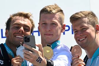 epa10036180 (L-R) Silver medalist Gregorio Paltrinieri of Italy, gold medalist Florian Wellbrock of Germany and bronze medalist Mykhailo Romanchuk of Ukraine pose for photographs during the award ceremony for the men's 5km open water swimming of the 19th FINA World Championships at Lupa lake near Budapest, Hungary, 27 June 2022.  EPA/Zsolt Szigetvary HUNGARY OUT