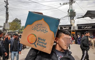 A man carries a cardboard box of food aid provided by non-profit non-governmental organisation World Central Kitchen in Rafah in the southern Gaza Strip on March 17, 2024, amid the ongoing conflict between Israel and the militant group Hamas. (Photo by MOHAMMED ABED / AFP)