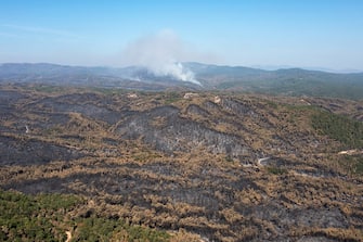 Smoke rises from a hill beyond burnt forest areas following a wildfire in the National Park of Dadia, Alexandroupolis, Greece, on Tuesday, Aug. 29, 2023. With more than 72,000 hectares burnt, the Alexandroupolis wildfire in Evros is the largest on record in the EU. Photographer: Konstantinos Tsakalidis/Bloomberg via Getty Images