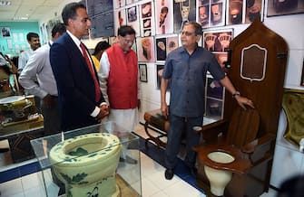 US Ambassador to India Richard Rahul Verma (L) and the founder of the Indian sanitation charity Sulabh International Bindeshwar Pathakat ((C) are shown varous models of toilets during a visit to Sulabh International Museum of Toilets in New Delhi on August 13, 2015.  During his visit Verma saw demonstrations of Sulabh's 'water ATM' and the bio-gas plant that runs on the byproducts of Sulabh toilets.  AFP PHOTO / MONEY SHARMA        (Photo credit should read MONEY SHARMA/AFP via Getty Images)