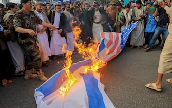People set a US and an Israeli flag on fire during a march to show solidarity with the Palestinians of the Gaza Strip on October 18, 2023, in the Houthi-controlled Yemeni capital Sanaa. Thousands rallied across the Arab and Muslim world on October 18 to protest the deaths of hundreds of people in a strike on a Gaza hospital that they blame on Israel, despite its denials. (Photo by MOHAMMED HUWAIS / AFP) (Photo by MOHAMMED HUWAIS/AFP via Getty Images)