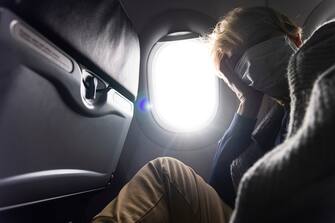 Tired mature women flying by airplane, during pandemic.