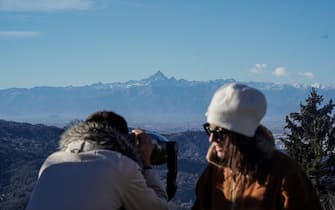 Turisti a Superga guardano dal binocolo verso Torino, in una giornata particolarmente limpida grazie alle forti raffiche di vento sul Torinese, 22 dicembre 2023. ANSA/JESSICA PASQUALON