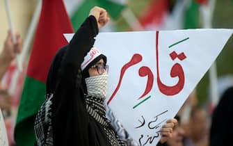 A protester holds an inverted 'red triangle' with a message written on its back, a symbol that the Palestinian Hamas movement's military wing Al-Qassam Brigades uses to identify Israeli targets in their videos, during a solidarity sit-in with the Gaza Strip, in Manama on November 17, 2023, amid ongoing battles between Israel and Hamas militants. (Photo by Mazen Mahdi / AFP) (Photo by MAZEN MAHDI/AFP via Getty Images)