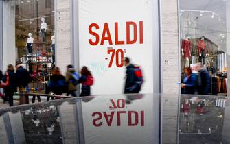 Persone davanti a una vetrina con articoli in saldo