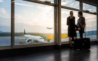 two business travellers standing at airport window and overlooking the airfield