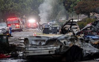 Firefighters work the site where a small plane crashed into a San Diego, California, residential street on May 22, 2025. The Federal Aviation Authority said a Cessna 550 crashed at around 3:45 am local time. The neighborhood is close to the Montgomery-Gibbs Executive Airport. The crash left a "gigantic debris field" and damaged some 15 homes and parked cars, ABC News quoted the San Diego assistant fire chief as saying. (Photo by Sandy Huffaker / AFP)