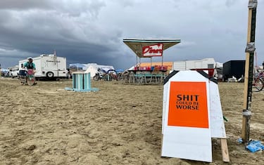 A sign reading "Shit Could Be Worse" as campers sit in a muddy desert plain on September 3, 2023, after heavy rains turned the annual Burning Man festival site in Nevada's Black Rock desert into a mud pit. Tens of thousands of festivalgoers were stranded September 3, in deep mud in the Nevada desert after rain turned the annual Burning Man gathering into a quagmire, with police investigating one death.
Video footage showed costume-wearing "burners" struggling across the wet gray-brown site, some using trash bags as makeshift boots, while many vehicles were stuck in the sludge. (Photo by Julie JAMMOT / AFP) (Photo by JULIE JAMMOT/AFP via Getty Images)