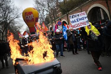 A protestor holds a placard which reads "Empty Fridge equals Violence of Dispair" in front of a pile of burning rubbish on the sidelines of a demonstration as part of a nationwide day of strikes and protests called by unions over the proposed pensions overhaul, in Paris on March 11, 2023. - The reform proposed by the government includes the raise of the minimum retirement age from 62 to 64 years and the increase of the number of years people have to make contributions for a full pension. Unions have vowed to keep up the pressure on the government, with a seventh day of mass protests, and some have even said they would keep up rolling indefinite strikes. (Photo by Christophe ARCHAMBAULT / AFP) (Photo by CHRISTOPHE ARCHAMBAULT/AFP via Getty Images)
