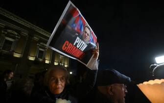 A woman holds a portrait of Kremlin's critic Alexei Navalny during a vigil in his honor following is death, on February 19, 2024 in front of Rome's city hall. The poster reads 'Putin criminal'. Russia reported Navalny's death in an arctic prison on February 16, 2024 and his mother has been denied access to the body, enraging supporters who have accused authorities of trying to cover up Navalny's "murder". (Photo by Filippo MONTEFORTE / AFP) (Photo by FILIPPO MONTEFORTE/AFP via Getty Images)