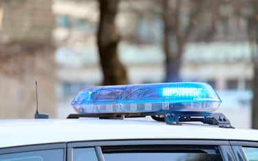 a close-up view of a police vehicle with blue lights patrolling near a public park with the windows and doors closed