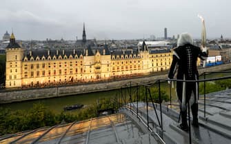 PARIS, FRANCE - JULY 26: A torchbearer carries the Olympic flame over a building along the Seine River during the Opening Ceremony of the Olympic Games Paris 2024 on July 26, 2024 in Paris, France. (Photo by Bernat Armangue - Pool/Getty Images)