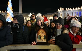 Faithful gather in front of the basilica at St Peter's square during the Christmas Eve mass  in the Vatican on December 24, 2024. Pope Francis marks Christmas Eve with a special ceremony launching Jubilee 2025, a year of Catholic celebrations set to draw more than 30 million pilgrims to Rome. Over the next 12 months, pilgrims will pass through the large and imposing bronze door, which is normally closed, by tradition benefiting from a "plenary indulgence", a type of forgiveness for their sins. (Photo by Alberto PIZZOLI / AFP)