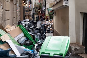 Pedestrians walk past waste that has been piling up on the pavement as waste collectors are on strike since March 6 against the French government's proposed pensions reform, in Paris on March 13, 2023. (Photo by ALAIN JOCARD / AFP) (Photo by ALAIN JOCARD/AFP via Getty Images)
