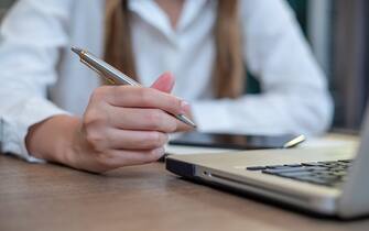 Woman sitting at desk and working at computer hands close up