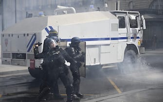 A French Riot Policeman standing next to a police water cannon throws a tear gas grenade towards protesters during a demonstration on May Day (Labour Day) to mark the international day of the workers, more than a month after the government pushed an unpopular pensions reform act through parliament, in Rennes, western France, on May 1, 2023. - Opposition parties and trade unions have urged protesters to maintain their three-month campaign against the law that will hike the retirement age to 64 from 62. (Photo by Damien MEYER / AFP) (Photo by DAMIEN MEYER/AFP via Getty Images)