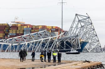 epa11244534 Rescue personnel gather on the shore of the Patapsco River after a container ship ran into the Francis Scott Key Bridge causing its collapse in Baltimore, Maryland, USA, 26 March 2024. The Maryland Department of Transportation confirmed that the Francis Scott Key Bridge collapsed due to a ship strike on 26 March. According to Baltimore City Fire Department Chief James W. Wallace, a search operation was underway to locate at least seven people believed to be in the waters of the Patapsco River following the incident. 'Sonar has detected the presence of vehicles submerged in the water', Wallace added. The Singapore-flagged cargo ship DALI was traveling from Baltimore to Colombo, Sri Lanka, MarineTraffic confirmed.  EPA/JIM LO SCALZO