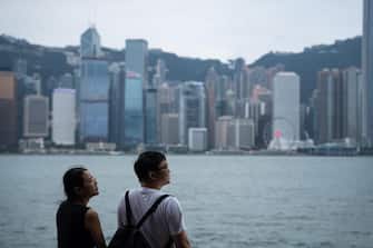 epa10832805 People look at the Hong Kong island skyline during Typhoon Saola in Hong Kong, China, 01 September 2023. The No.8 typhoon warning was raised on the morning of 01 September as Typhoon Saola arrived in Hong Kong.Â The stock market was closed and schools suspended in the city in response to the typhoon.  EPA/Bertha Wang