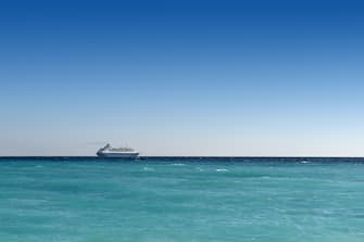 cruise liner sailing away on turquoise water and blue sky backround