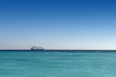 cruise liner sailing away on turquoise water and blue sky backround