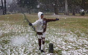 TOPSHOT - Gabriel Sussman gestures as snow falls in Zoo Lake park in Johannesburg on July 10, 2023. (Photo by Wikus de Wet / AFP) (Photo by WIKUS DE WET/AFP via Getty Images)