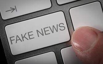A man pressing a key on a computer keyboard with the words Fake News, fake news concept image