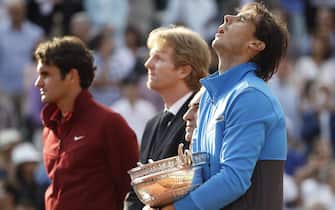 epa02767861 Rafael Nadal of Spain (R) holds his trophy while sharing the podium with Roger Federer (L) Jim Curier (2nd L), winner of 1991 and 1994 French Open, and the president of the French Tennis Federation Jean Gachassin (2nd R), during the awards ceremony at the end of the men's final match for the French Open tennis tournament at Roland Garros in Paris, France, 05 June 2011. Nadal beat Federer in four sets and it is his fourth victory over Federer at the French Open.  EPA/IAN LANGSDON