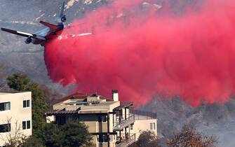 Los Angeles TOPANGA, CALIFORNIA - JANUARY 10: A person (BOTTOM) watches from a balcony as a firefighting aircraft drops the fire retardant Phos-Chek near homes during the Palisades Fire as wildfires cause damage and loss through Los Angeles County on January 10, 2025 in Topanga, California. Multiple wildfires fueled by intense Santa Ana Winds are burning across Los Angeles County. Reportedly at least 10 people have died with over 180,000 people having been under evacuation orders. Over 9,000 structures have been damaged or burned while more than more than 25,000 acres were burning from the fires. (Photo by Mario Tama/Getty Images)