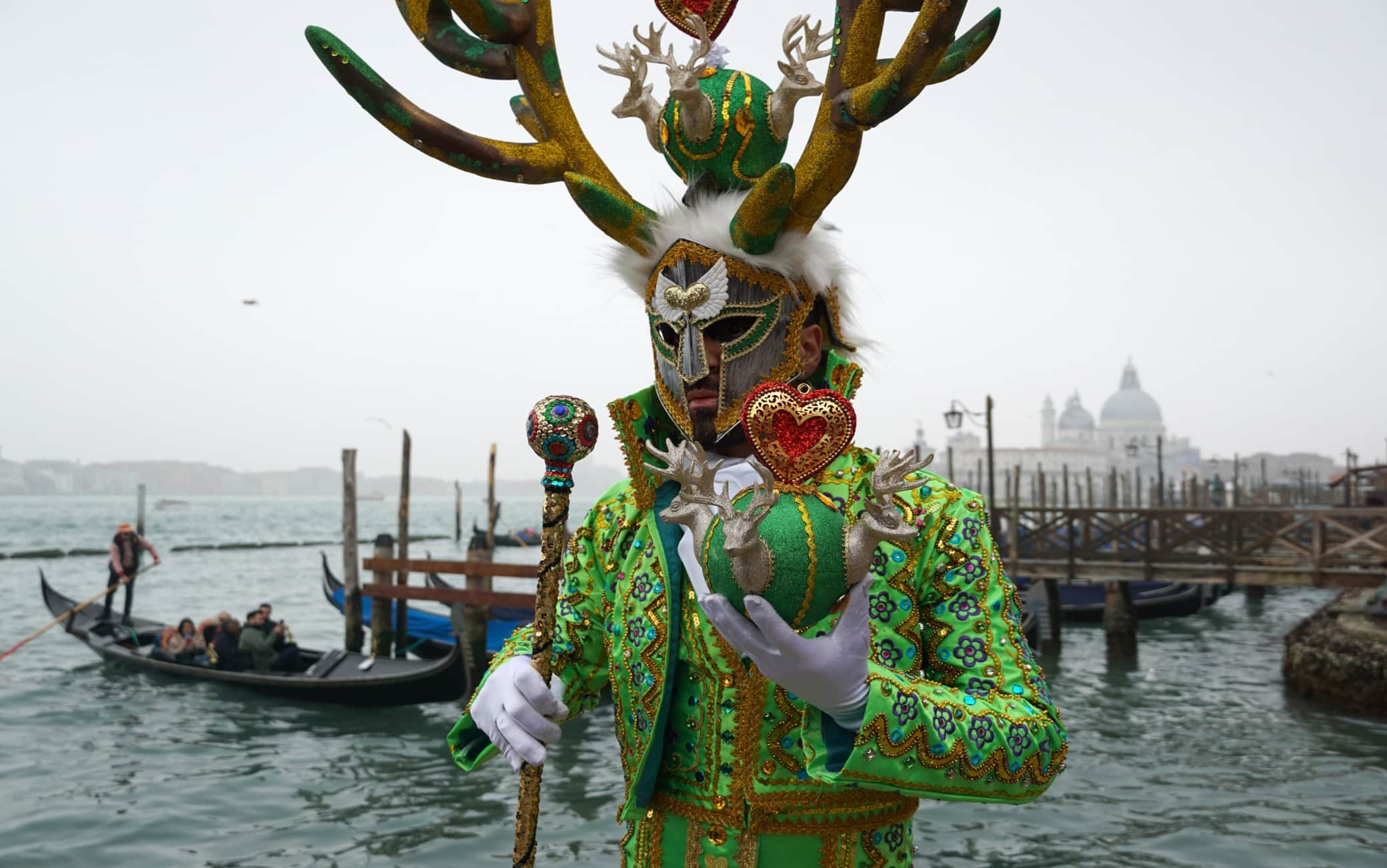 Un personaggio, vestito di un vistoso costume colorato,  posa sul molo di San Marco, per il carnevale veneziano, oggi 18 febbraio 2023. ANSA/ANDREA MEROLA