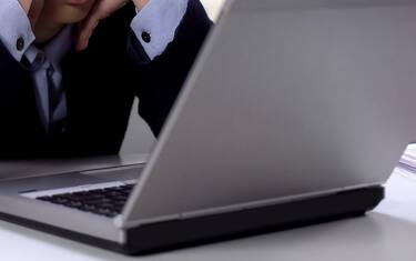 Exhausted female office worker waiting for important e-mail, looking at laptop