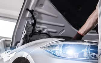 Modern Certified Car Service. Caucasian Mechanic in His 30s Checking Crucial Elements of the Engine During Scheduled Warranty Maintenance.