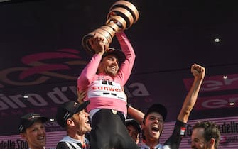 Dutch rider Tom Dumoulin holds up the trophy celebrating on the podium with his teammates of Sunweb after winning the 100th Giro d\