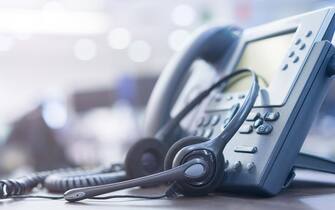 close up headset of call center and VOIP telephone for communication technology on office desk in monitoring room for network operation job concept