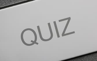 A man pressing a key on a computer keyboard with the word Quiz. Online quiz concept image.