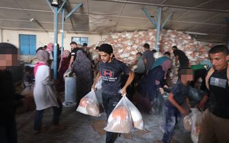 TOPSHOT - Palestinians storm a UN-run aid supply center, that distributes food to displaced families following Israel's call for more than one million residents in northern Gaza to move south for their safety, in Deir al-Balah on October 28, 2023, amid the ongoing battles between Israel and the Palestinian group Hamas. Thousands of civilians, both Palestinians and Israelis, have died since October 7, 2023, after Palestinian Hamas militants based in the Gaza Strip entered southern Israel in an unprecedented attack triggering a war declared by Israel on Hamas with retaliatory bombings on Gaza. (Photo by MOHAMMED ABED / AFP) / "The erroneous mention[s] appearing in the metadata of this photo by MOHAMMED ABED has been modified in AFP systems in the following manner: [Storm] instead of [Collect boxes and and bags from]. Please immediately remove the erroneous mention[s] from all your online services and delete it (them) from your servers. If you have been authorized by AFP to distribute it (them) to third parties, please ensure that the same actions are carried out by them. Failure to promptly comply with these instructions will entail liability on your part for any continued or post notification usage. Therefore we thank you very much for all your attention and prompt action. We are sorry for the inconvenience this notification may cause and remain at your disposal for any further information you may require." (Photo by MOHAMMED ABED/AFP via Getty Images)